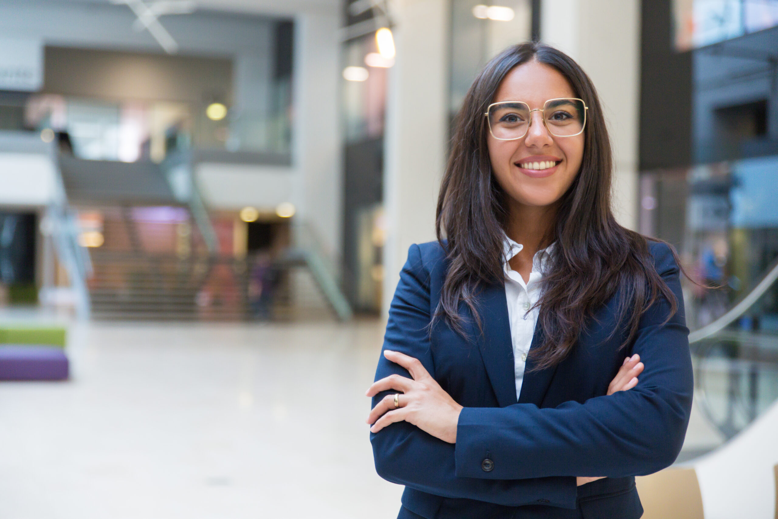 Young businesswoman smiling at camera Young businesswoman smiling at camera. Portrait of cheerful Hispanic businesswoman in formal wear standing with crossed arms and looking at camera. Business concept