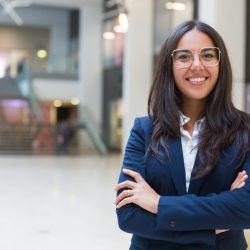 Young businesswoman smiling at camera Young businesswoman smiling at camera. Portrait of cheerful Hispanic businesswoman in formal wear standing with crossed arms and looking at camera. Business concept